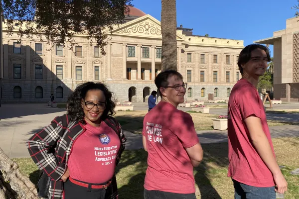 Three people outside the Arizona State Capitol. All three wear red tshirts. Front of tshirt says Higher Education Legislative Advocacy Day. Back says Together, We Can Change the Law.