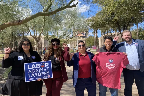 Five people standing in front of the Arizona Capitol, holding up solidarity fists.