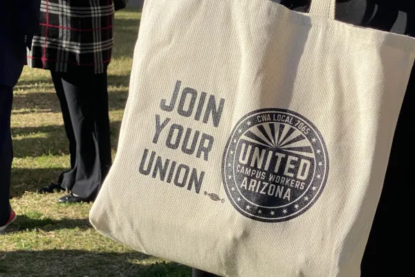 Person holding a tote bag that says "join your union" accompanied by the UCWAZ logo.